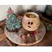 This is Fraser the Elf with his hat off, placed next to him. You can see the inside of the gourd is unfinished. Jingle bells lay nearby. 